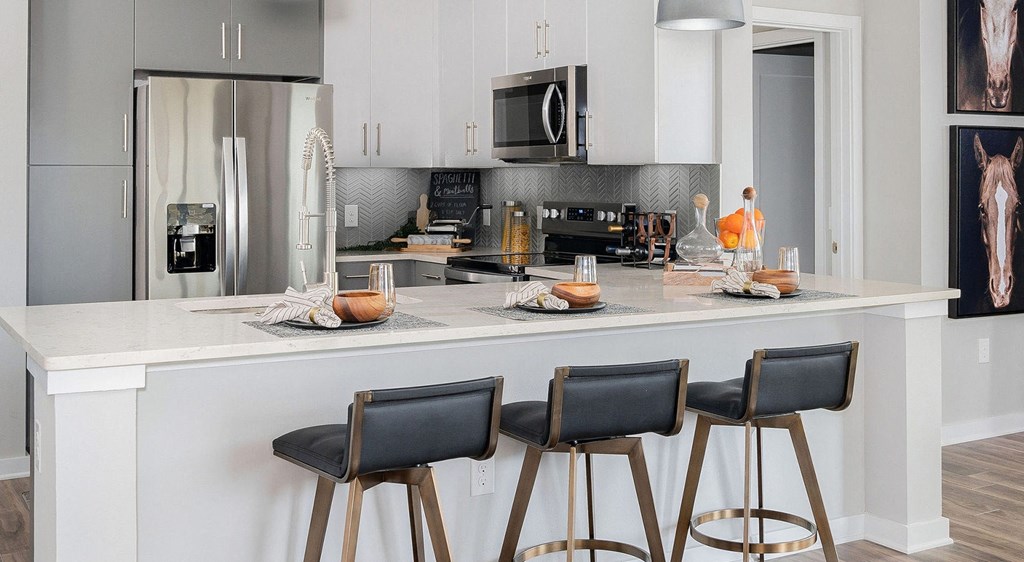 a kitchen with a counter with three bar stools