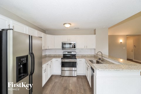 A kitchen with a refrigerator, sink, and cabinets.