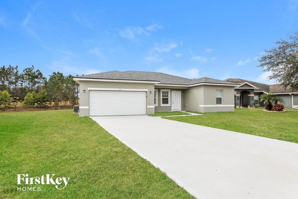 a beige house with a garage and a lawn