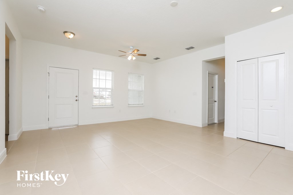 an empty living room with white doors and a ceiling fan