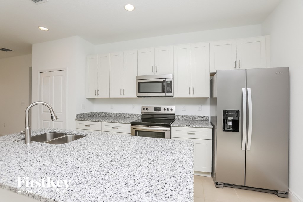 a white kitchen with granite counter tops and stainless steel appliances