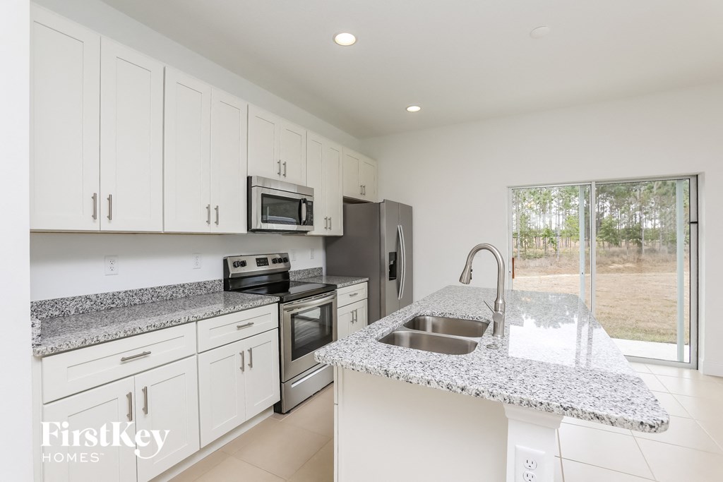 a kitchen with white cabinets and granite counter tops and a sink