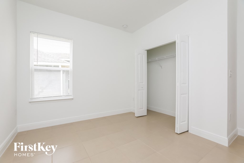 a bedroom with a closet and a window and a tiled floor