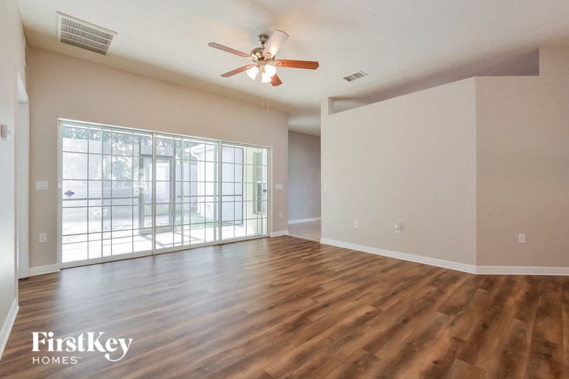 an empty living room with a ceiling fan and a window