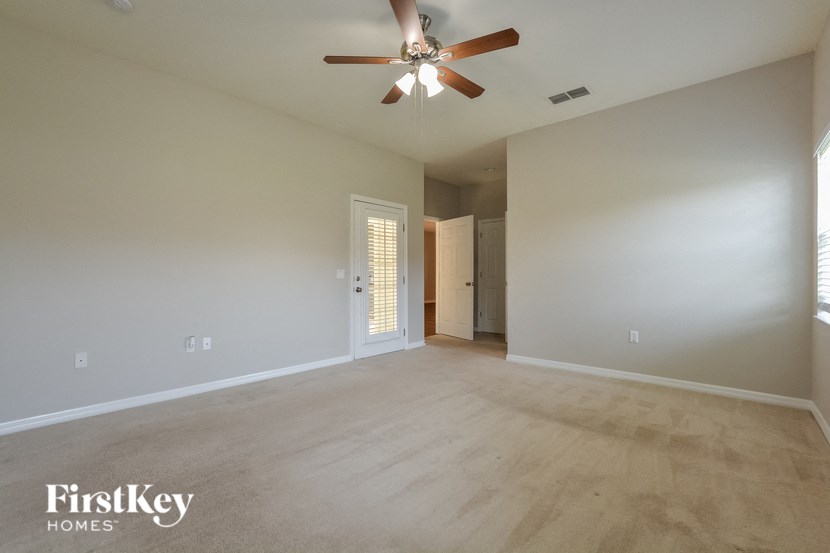 an empty living room with a ceiling fan and a white wall