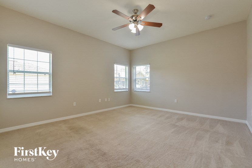 an empty living room with a ceiling fan and two windows