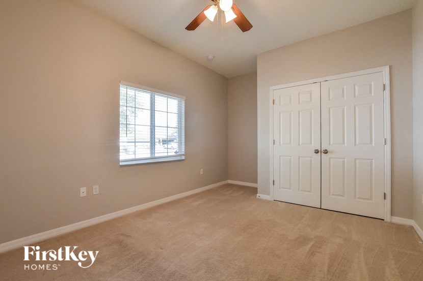 a bedroom with a carpeted floor and a window and two doors