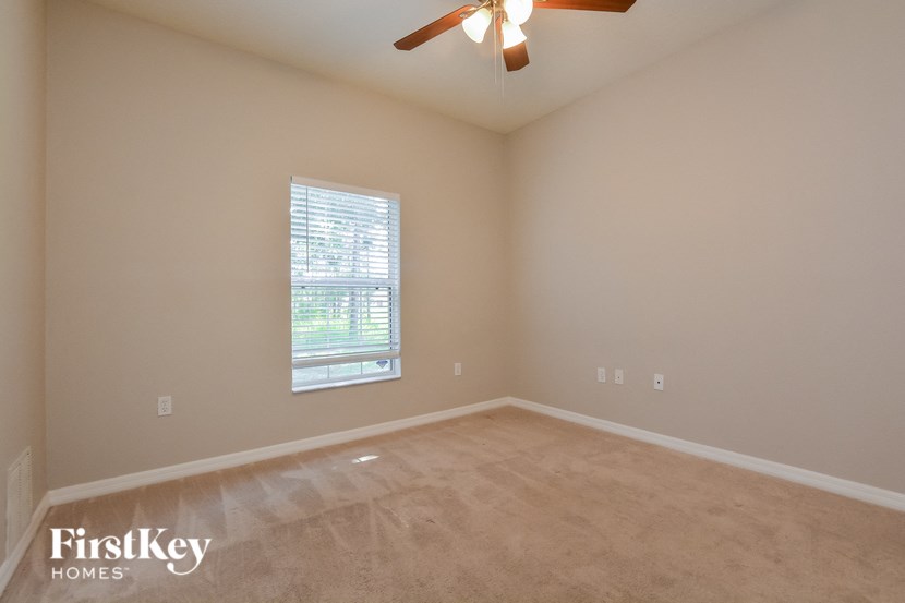 an empty living room with a window and a ceiling fan