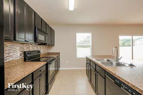 A kitchen with black cabinets and a granite countertop.