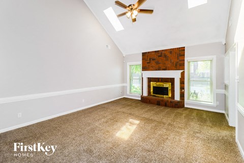 A spacious room with a fireplace and a ceiling fan.
