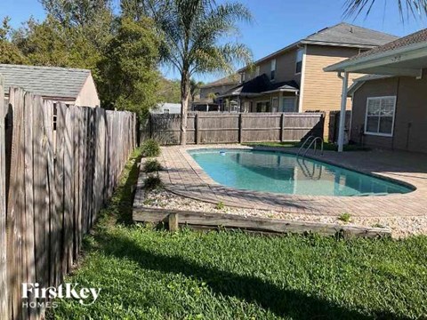 A pool surrounded by a wooden fence in a backyard.