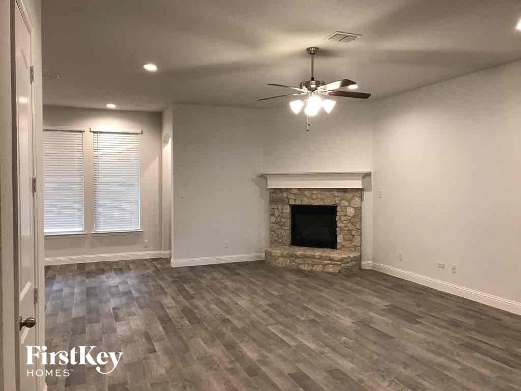 A spacious room with a fireplace and a ceiling fan.