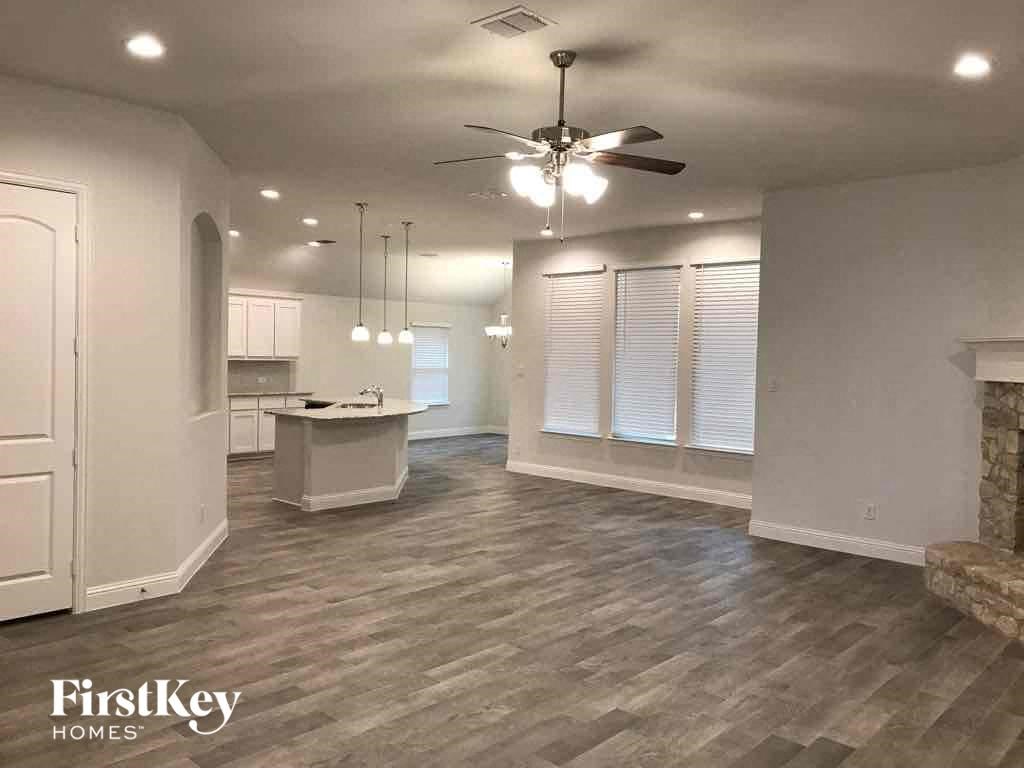 A spacious room with a fireplace and a kitchen area.