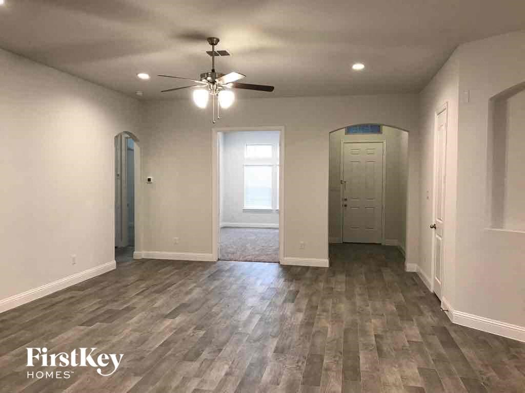 A room with a ceiling fan and wooden flooring.