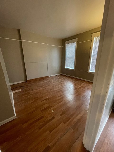 A room with wooden flooring and a window with blinds.