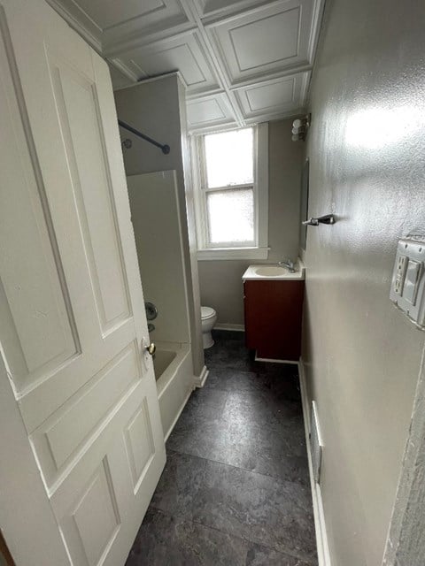 A bathroom with a toilet, sink, and window.