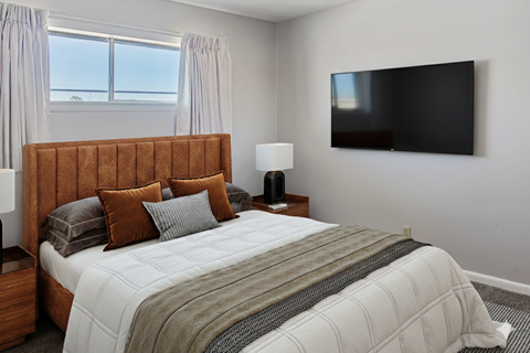 A bedroom with a large bed and a flat screen TV mounted on the wall.