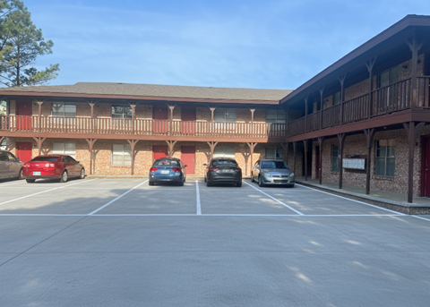 A parking lot with cars and a building with a balcony.