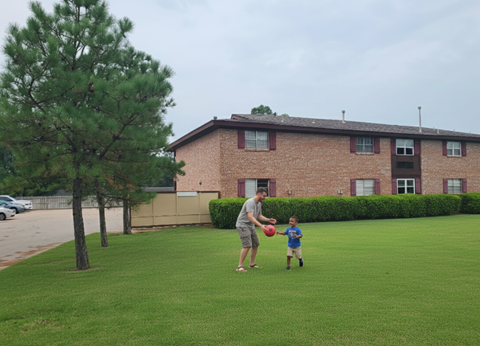 A man and a child are playing with a ball in a grassy area.