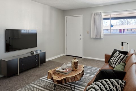 A living room with a brown couch, a wooden coffee table, and a flat screen TV.