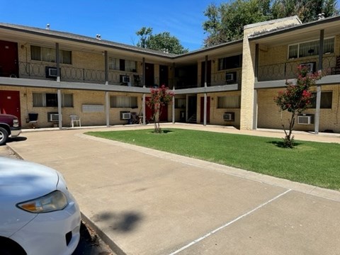 A white car is parked in a parking lot in front of a building.