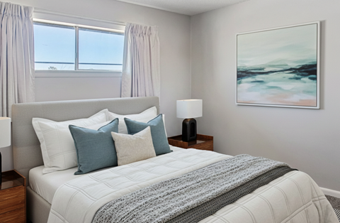 A bedroom with a large bed and a painting on the wall.