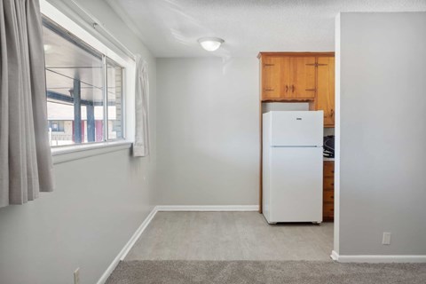 A white refrigerator in a kitchen with a window and curtains.