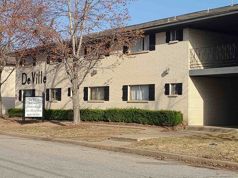 A DeVille apartment complex is on the corner of a street.