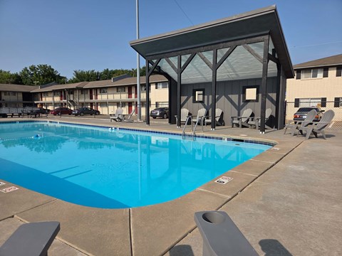 A large swimming pool with a pavilion in the background.