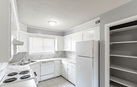 A white kitchen with a refrigerator and a stove.