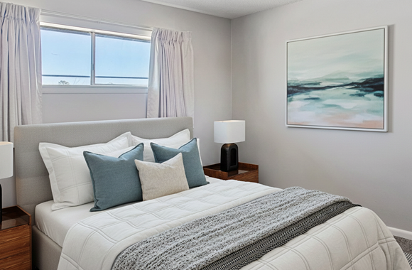 A bedroom with a large bed and a painting on the wall.