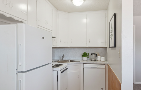 A white fridge in a kitchen with a stove and dishwasher.