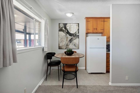 A kitchen with a table and chairs in the foreground and a refrigerator in the background.