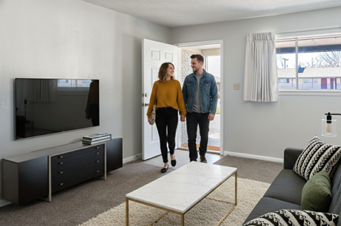 A man and woman are standing in a living room.