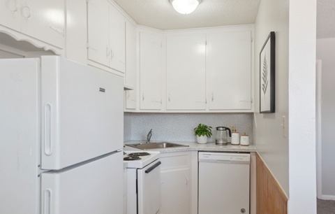 A white fridge in a kitchen with a stove and dishwasher.