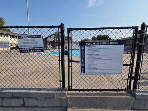 A sign on a fence outlines the rules and regulations for a pool.