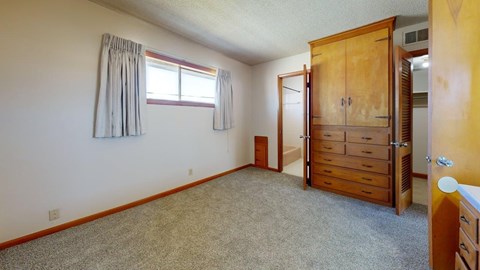 A room with a wooden wardrobe and a carpeted floor.