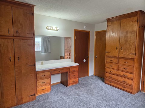 A room with a desk and a large wooden cabinet.
