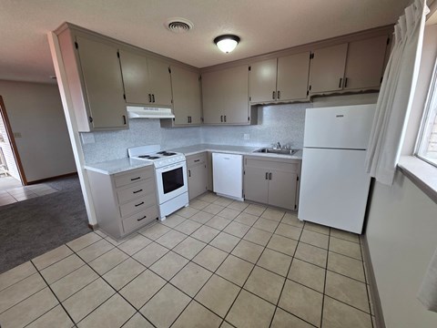A kitchen with white appliances and beige cabinets.