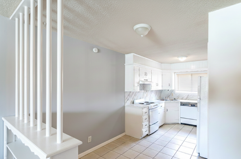 A white kitchen with a white fridge, stove, and dishwasher.
