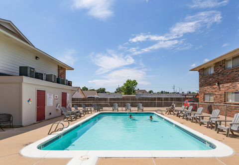 A swimming pool surrounded by lounge chairs and buildings.