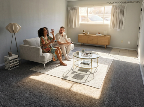 A couple is sitting on a couch in a living room with a coffee table in front of them.