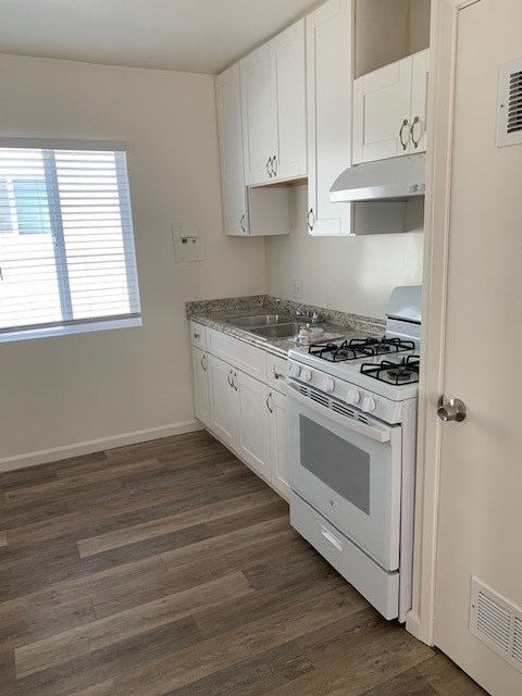 A white kitchen with a stove and a window.