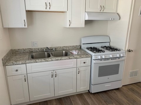 A kitchen with a white stove and cabinets.