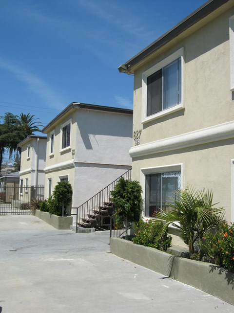 A white house with a black railing and a palm tree in front.