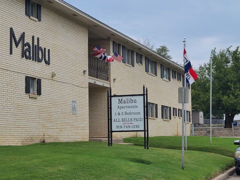 A building with the name Malibu on it and a sign that says Malibu Apartments & 2 Bedroom.