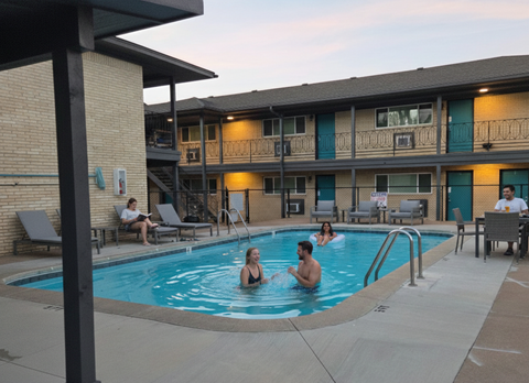 A group of people are enjoying a swim in a pool at a resort.