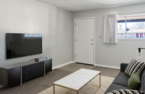 A living room with a black couch, a white coffee table, and a black and white striped throw blanket.