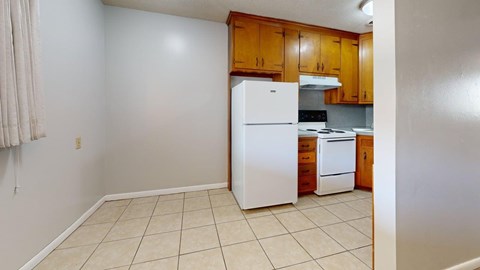 A kitchen with a white refrigerator and wooden cabinets.