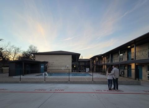 A couple is standing in front of a building with a pool and a fire lane.